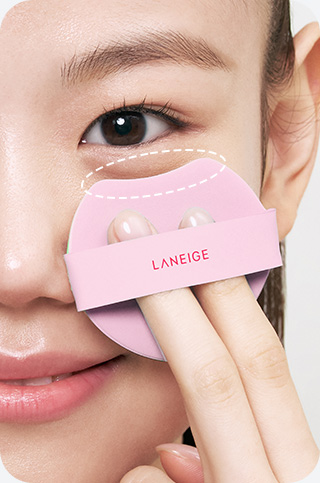 모델이 네오 쿠션 더 글로우 퍼프로 눈 아래를 바르는 모습